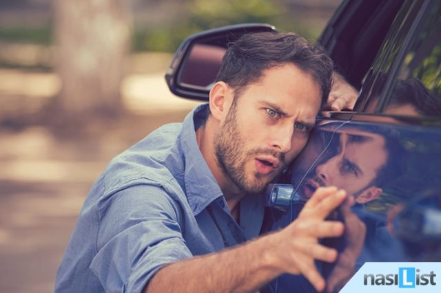 Frustrated upset young man looking at scratches and dents on his car outdoors